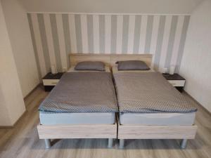 two twin beds in a room with two tables at Apartman ŠIPA in Bjelovar