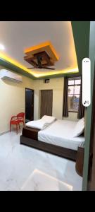 a bedroom with two beds and a red chair at Hotel kanha Royal Inn in Jodhpur