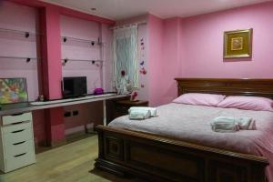 a bedroom with pink walls and a bed and a desk at Casa Vacanze Chiara in Terni