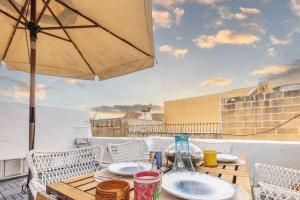 a wooden table with chairs and an umbrella on a balcony at Elegant Maltese Townhouse in Attard