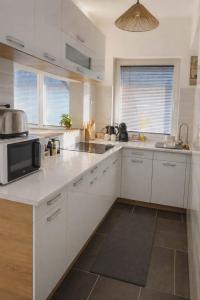 a kitchen with white cabinets and a microwave at GRAND HOME Apartman in Sárospatak