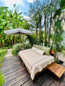 a bed on a wooden deck with an umbrella at Casas das Piçarras - Alentejo in Piçarra
