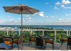 a patio with tables and chairs and an umbrella at Private Oasis at Arya in Miami
