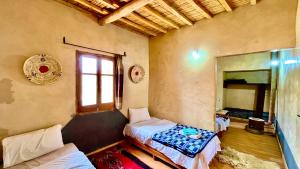 a room with two beds and a mirror at Kasbah Restaurant Citoyenne in Agoudal