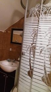 a bathroom with a shower curtain with a palm tree mural at Pensiunea Taverna Bucium in Iaşi