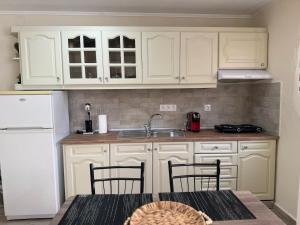 a kitchen with white cabinets and a table with chairs at Alexandra Apartment in Agíasma +7 photos