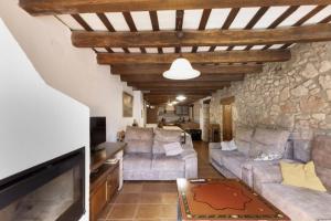 a living room with couches and a stone wall at Cal Vidal in Mura