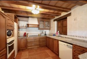 a large kitchen with wooden cabinets and white appliances at Cal Vidal in Mura