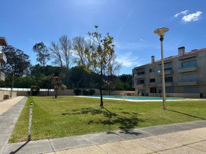 a park with a tree in the grass next to a building at Ofir Beach Apartment in Fão