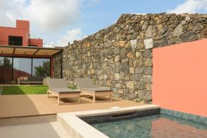 a patio with two chairs next to a stone wall at Villa São Roque in Ponta Delgada