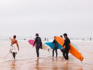 a group of people standing on the beach holding surfboards at Tamraght Surf House in Tamraght Ouzdar