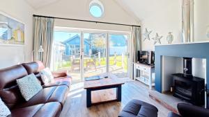 a living room with a couch and a fireplace at Puffin Lodge - Part of the The Bay Filey Holiday Village with pool, gym and direct beach access, pub, restaurant, tennis and meadows walks in Filey