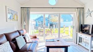 a living room with a couch and a sliding glass door at Puffin Lodge - Part of the The Bay Filey Holiday Village with pool, gym and direct beach access, pub, restaurant, tennis and meadows walks in Filey