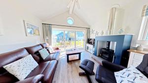 a living room with a leather couch and a fireplace at Puffin Lodge - Part of the The Bay Filey Holiday Village with pool, gym and direct beach access, pub, restaurant, tennis and meadows walks in Filey