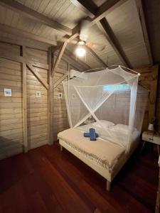 a bed with a plastic canopy in a room at Le MORNE Aux F0US Cabanes & Jardin Tropical in Deshaies