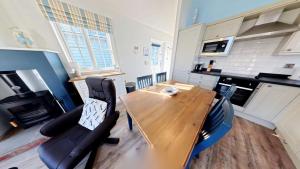 a kitchen with a wooden table and black chairs at Puffin Lodge - Part of the The Bay Filey Holiday Village with pool, gym and direct beach access, pub, restaurant, tennis and meadows walks in Filey +43 photos