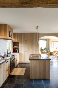 a large kitchen with wooden cabinets and a large island at De Zonnebrug in Sint-Laureins