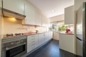 a kitchen with white cabinets and a stainless steel refrigerator at GuestReady - Retreat in Almada in Almada