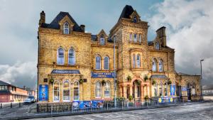 a large brick building with a fence in front of it at Patten Arms Hotel in Warrington