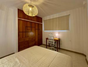 a bedroom with a bed and a desk and a chandelier at BoHo Galapagos in Puerto Ayora