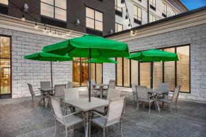 a group of tables and chairs with green umbrellas at Holiday Inn Quincy by IHG in Quincy