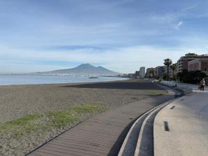 a sidewalk next to a beach with a mountain at Pepe Apartments Asy in Castellammare di Stabia