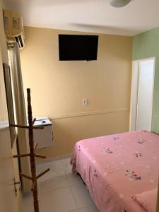 a bedroom with a bed and a tv on the wall at Pousada Extensão Sabrinna in Maceió
