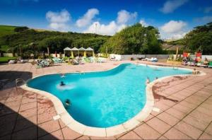 a large swimming pool with people sitting around it at Sunshine Newquay Bay Resort in Newquay Bay Resort