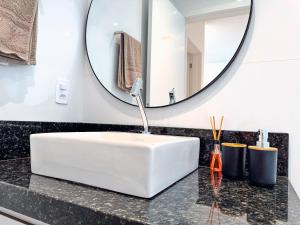 a bathroom with a white sink and a mirror at Flat moderno com churrasqueira próximo à Unifebe in Brusque +13 photos