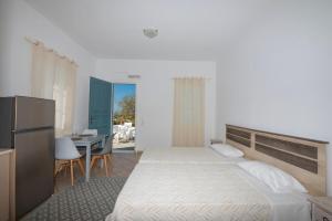 a bedroom with a bed and a table and a refrigerator at Sunset 7.59 in Mikonos