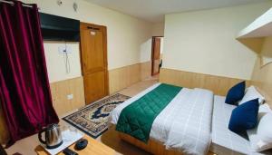 a bedroom with a bed with blue and green pillows at CL Villa Manali in Manāli