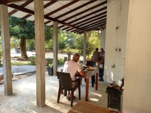 a man sitting at a table under a pergola at Silent Peacock Villa And Restaurant in Tangalle