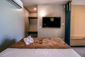 a room with a bed with a tv and a bedspread at Studio perfeito na Rota de Milagres in Pôrto de Pedras