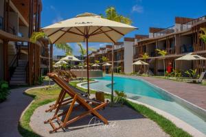 a chair with an umbrella next to a swimming pool at Studio perfeito na Rota de Milagres in Pôrto de Pedras