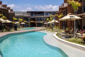 a swimming pool with umbrellas in a resort at Studio perfeito na Rota de Milagres in Pôrto de Pedras