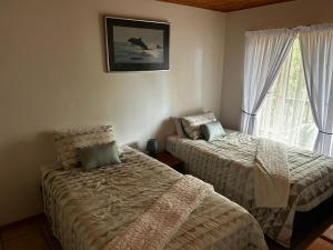 a bedroom with two beds and a window at Die Anker Kothuis in Southbroom