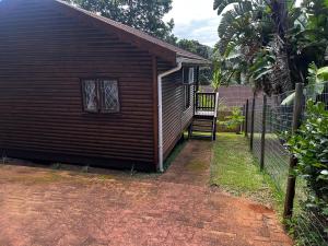a small house with a staircase next to a fence at Die Anker Kothuis in Southbroom