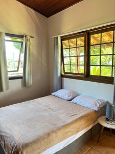 a bedroom with a bed and two windows at Micas House in Ilhabela +13 photos