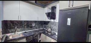 a kitchen with white cabinets and a black refrigerator at Rest House İsmayıllı A frame in İsmayıllı +7 photos