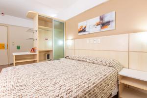 a small bedroom with a bed and a desk at Hotel Metropolitan Canoas in Canoas