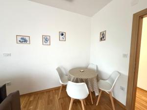 a dining room with a table and white chairs at Zenith Apartment - Herceg Novi & Beach & Private Parking in Bijela