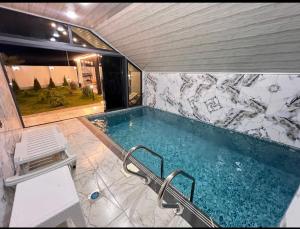 a swimming pool in a room with a stone wall at Rest House İsmayıllı A frame in İsmayıllı