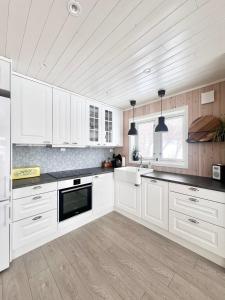 a kitchen with white cabinets and black counter tops at Ocean View Cottage in Alta