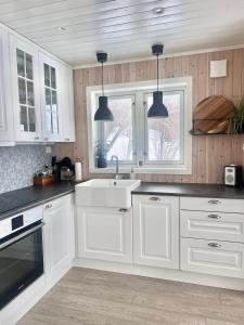 a kitchen with white cabinets and a sink and two lights at Ocean View Cottage in Alta +17 photos