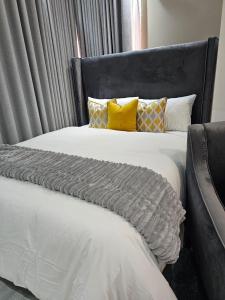a large bed with a black headboard and yellow pillows at Millenium Heights Borrowdale in Harare