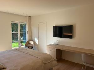 a bedroom with a bed and a desk with a tv at Villa Kokeliko in Kuurne