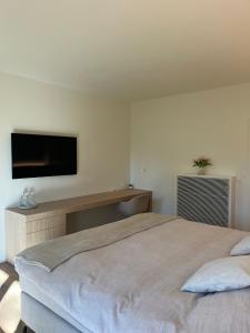 a bedroom with a large bed and a flat screen tv at Villa Kokeliko in Kuurne