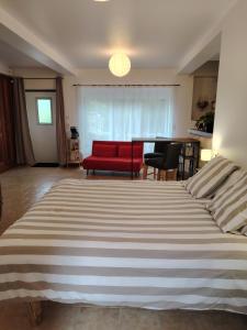 a bedroom with a large bed and a red couch at Studio Magnolia in Saint-Satur