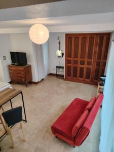 a living room with a red couch and a tv at Studio Magnolia in Saint-Satur