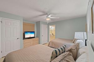 a bedroom with two beds and a flat screen tv at Barefoot Getaway in Orange Beach